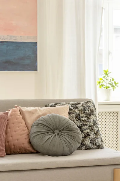 Grey and pastel pink pillows on trendy Scandinavian couch in elegant interior with painting on the white wall — Stock Photo, Image