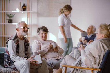 Gülümseyen yaşlı adam emeklilik diğer sakinleri ile konuşurken 