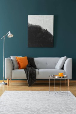 Yeşil bir duvarda boyama, kanepe yastık ve halı ile dekore edilmiş bir oturma odası iç. Gerçek fotoğraf