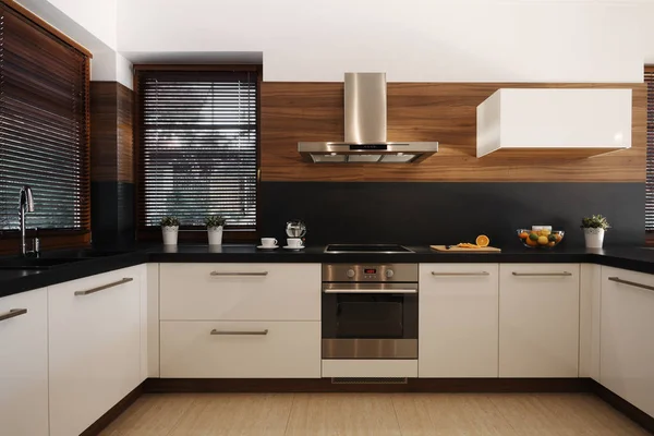 Elegante cocina blanca y negra con acentos de madera y horno de plata y fregadero — Foto de Stock