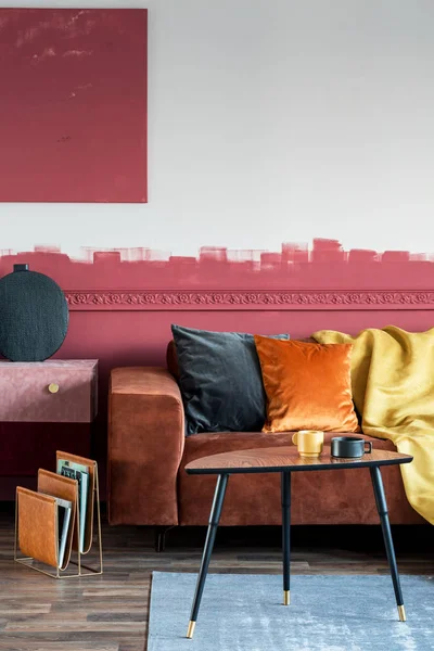 Almohada naranja en sofá marrón en el interior de la sala de estar de moda con cómoda de gamuza y mesa de centro de madera — Foto de Stock