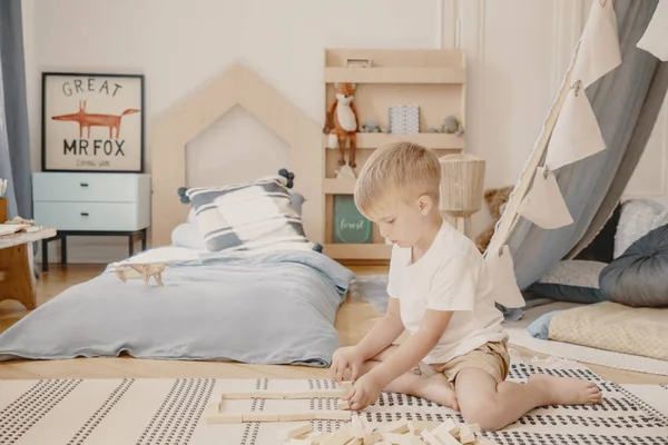 Jongen spelen met houten blokken in een kinderkamer interieur — Stockfoto