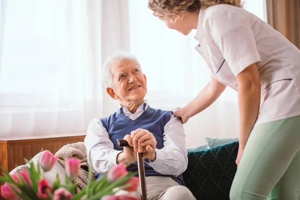 Старший мужчина с тростью утешается медсестрой в — стоковое фото