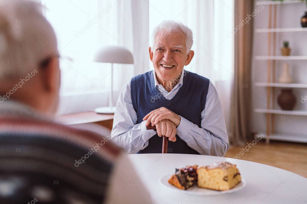 Happy senior man laughing with his old friend over the piece of 