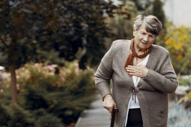 Nefes darlığı saldırısı sırasında yardım bekleyen bastonile zayıf yaşlı kadın