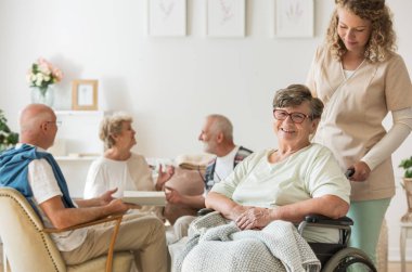 Onu destekleyen profesyonel caregiver ile tekerlekli sandalye üzerinde kıdemli kadın
