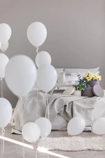 Chambre contemporaine design intérieur avec lit confortable avec draps gris, boîtes rondes fleurs et ballons blancs — Photo