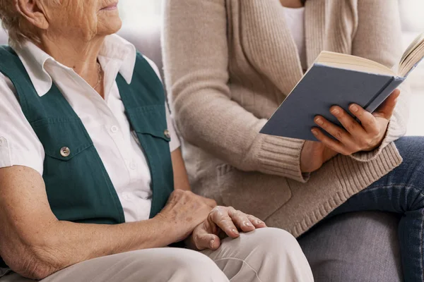 Starszy kobieta i pomocny wolontariusz w domu opieki czytania książki razem — Zdjęcie stockowe