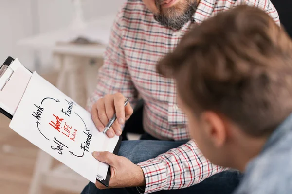 Personal life coach explaining graph to his young patient — Stock Photo, Image
