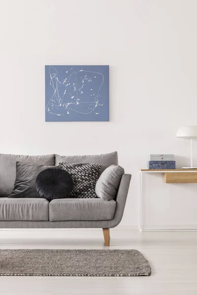 Blå abstrakt målning på vit vägg av fashionabla vardags rum interiör med grå soffa och konsol bord — Stockfoto
