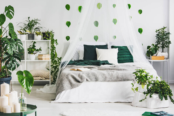 White bedroom interior with king size bed, urban jungle and green leaf on the wall