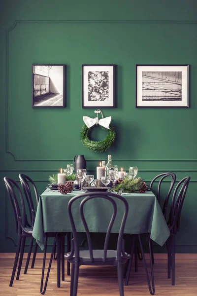 Elegante eettafel met wijnglazen, borden en kaarsen voor kerstdiner, Galerij van zwarte en witte affiches op lege grijze muur — Stockfoto