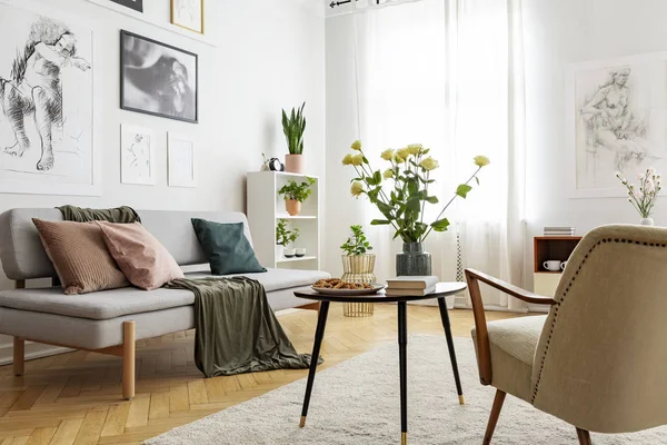 포스터와 밝은 거실 인테리어에 세 티와 안락의자 사이 테이블에 꽃. 실제 사진 — 스톡 사진