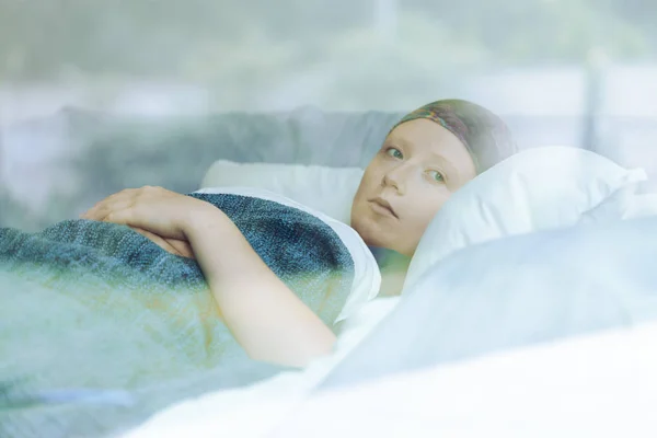 Mujer reflexiva luchando contra el tumor que yace en la cama del hospicio —  Fotos de Stock