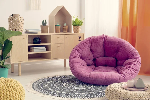 Rosa bequemer Hocker inmitten eines eleganten natürlichen Kinderzimmers mit Holzmöbeln und Ethno-Design — Stockfoto