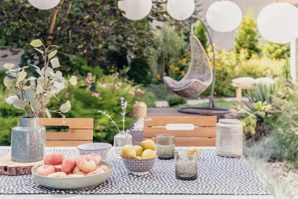 Növény-és élelmiszer-asztalon a kertben elmosódott lógó szék a háttérben — Stock Fotó