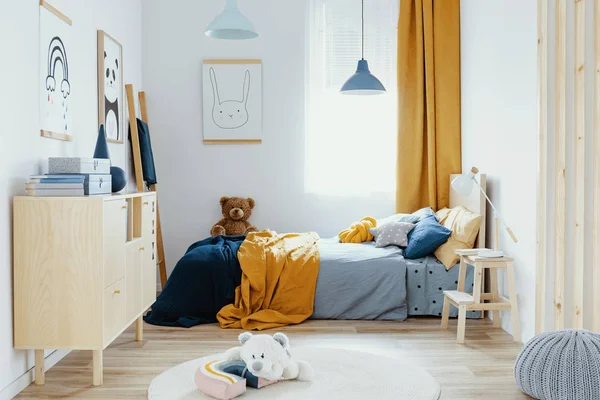 Osito de peluche en una cama individual de madera en el interior del dormitorio azul y naranja —  Fotos de Stock