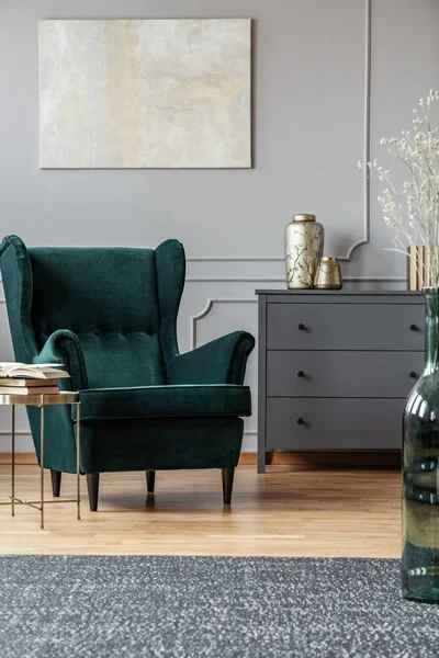 Mesa de café elegante ao lado de poltrona verde esmeralda no interior da sala de estar na moda com design cinza — Fotografia de Stock