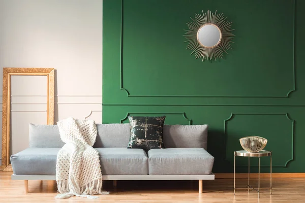 Forma de sol dourado como espelho na parede verde da sala de estar interior com sofá escandinavo com almofadas — Fotografia de Stock