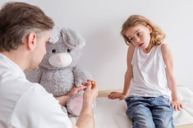 Üzgün hasta çocuk ve doktor muayenehanesinde çocuk doktoru