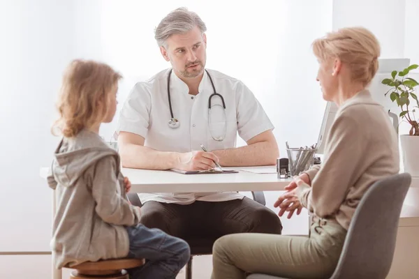 Mutter und süßer kranker Sohn vor dem hübschen Kinderarztpult — Stockfoto