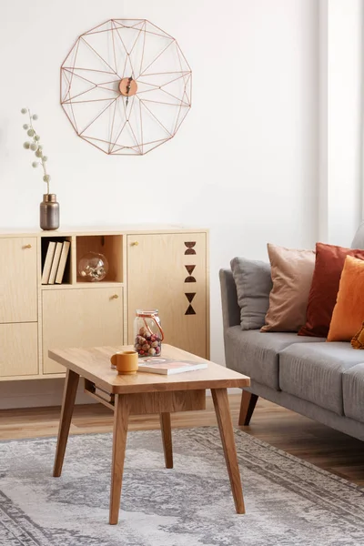 Винтажный деревянный журнальный столик и комод в элегантном интерьере гостиной с серым диваном — стоковое фото