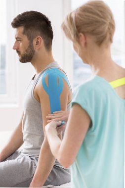 Fizyoterapist kinesiotaping tedavisi sırasında özel yapı yamaları ile genç adamın vücudunun seçilmiş parçaları kapsayan