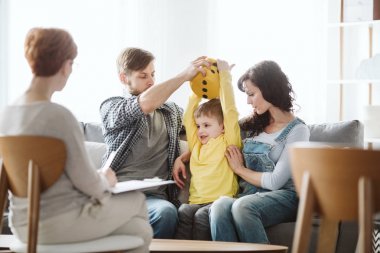 Cute little boy with ADHD during session with professional therapist clipart