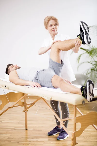 Handsome young man during physiotherapy session with professional doctor — Stock Photo, Image