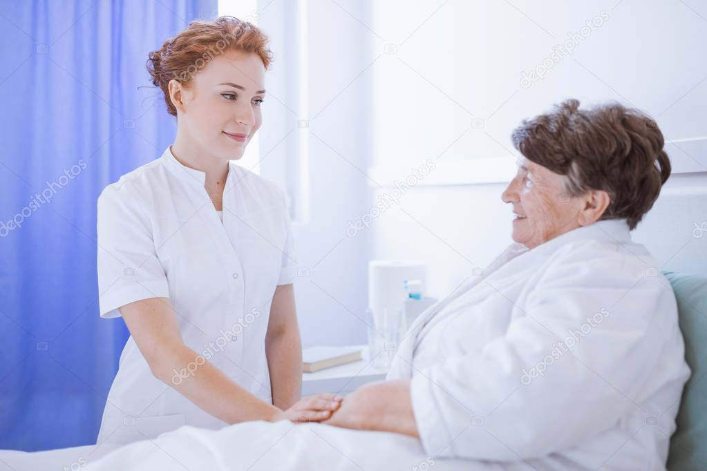 Young beautiful female doctor and senior patient at hospital