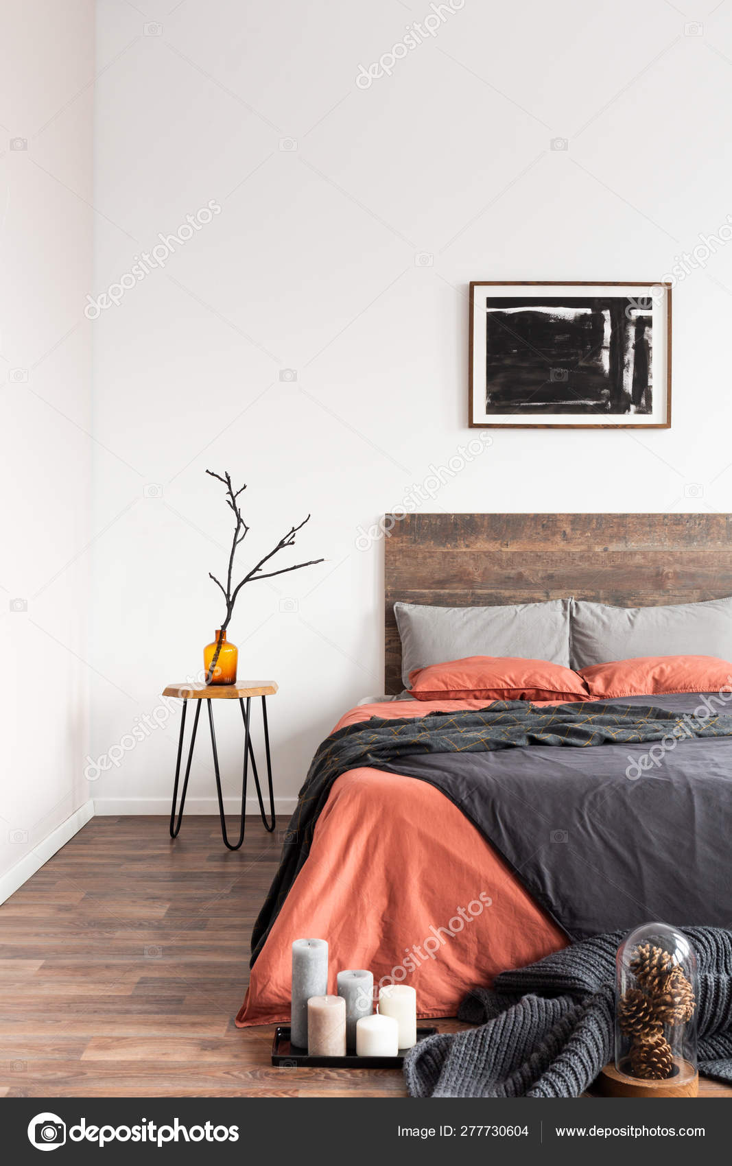 Comfy bed with grey and salmon bedding and pillows with bedside
