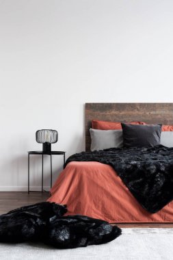 Siyah kürklü battaniye ve beyaz mercan yatak örtüleri üzerinde yastıklar