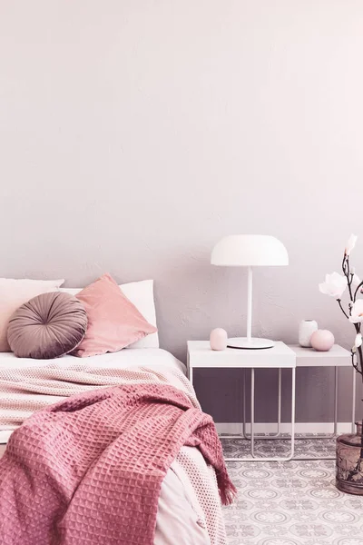 White industrial lamp on nightstand table next to king size bed with white bedding and pastel pink pillows and blanket — Stock Photo, Image