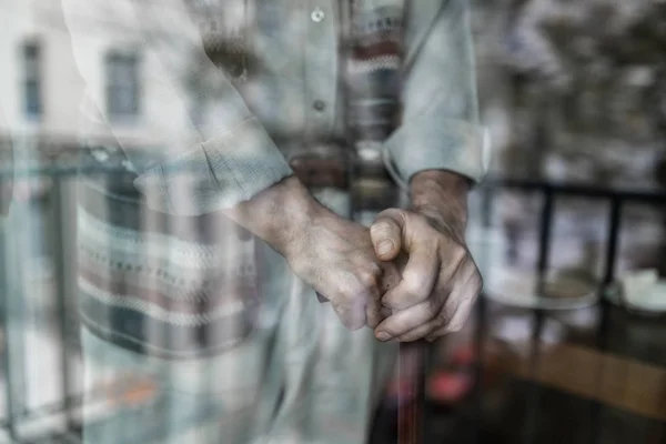 Grâce à la prise de vue en verre des mains de l'homme âgé soutenu sur la canne en bois — Photo