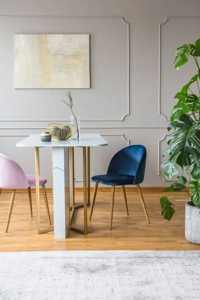 Table grise et dorée dans la salle à manger avec fauteuils rose et bleu — Photo