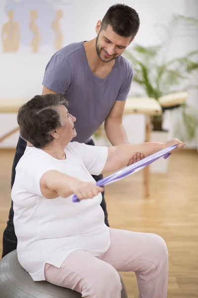 Rentnerin trainiert mit ihrem Physiotherapeuten mit Widerstandsbändern — Stockfoto