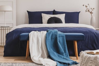 Zarif yatak odasında bankta açık mavi ve beyaz battaniye