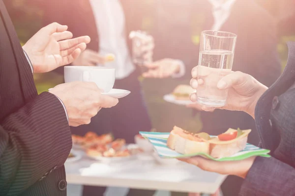 Closeup of Man and woman holding coffee, water and sandwiches during business lunch — Stock Photo, Image