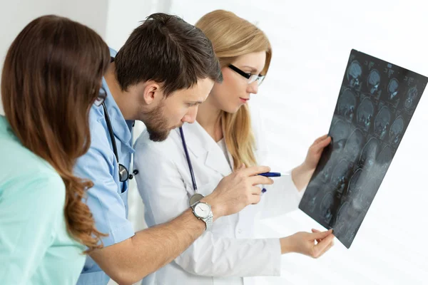 Bonito jovem médico apontando para o exame de raios X durante a consulta médica — Fotografia de Stock