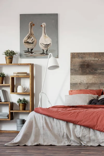 Rustic poster with two ducks, wooden bookshelf and double bed with pillows and duvet — Stock Photo, Image