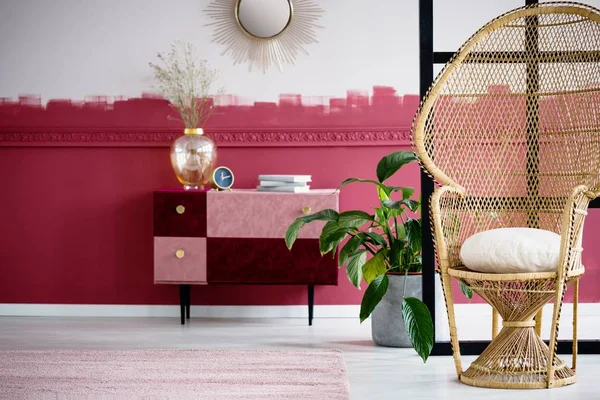 Hasır tavus kuşu koltuğu ve el yapımı pastel pembe ve çekmeceli Bordo göğüs ile trendy oturma odası iç — Stok fotoğraf