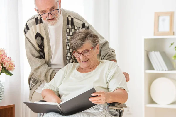 Счастливая пожилая супружеская пара с фотоальбомом в доме престарелых — стоковое фото