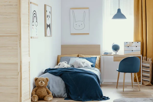 Стол, стул и односпальная кровать с голубыми кроватями в уютном интерьере спальни для детей — стоковое фото