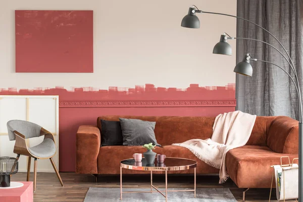 Бархатные серые и черные подушки на удобном коричневом диване в элегантной гостиной с белой и красной стеной — стоковое фото