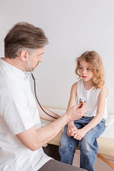 Helpful pediatrician and sick blond boy in a doctor's office