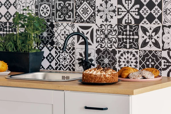 Birthday cake on kitchen counter in elegant interior with black and white wall — Stock Photo, Image