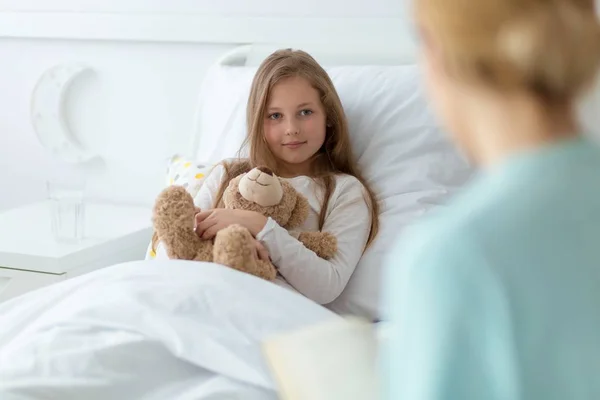 Chica en el hospital sosteniendo un oso de peluche — Foto de Stock