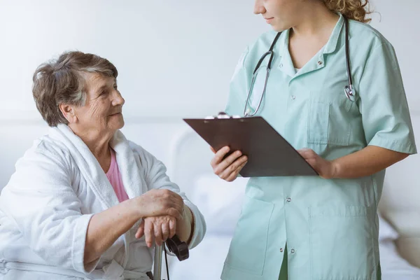 Giovane medico stagista con pad e stetoscopio e nonna anziana con canna — Foto Stock
