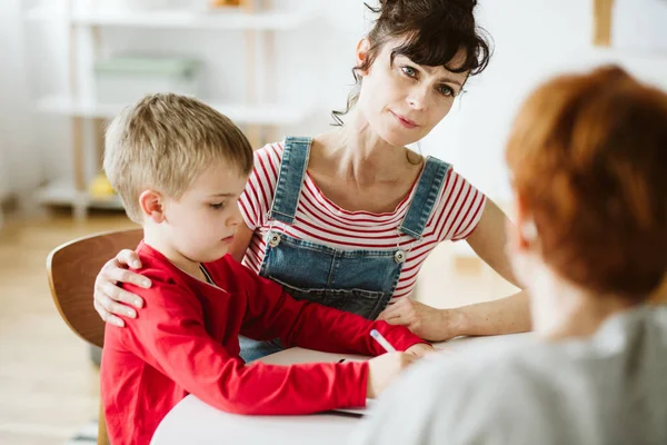 Moeder en en kleine jongen in rode trui leren door te tekenen tijdens ADHD-therapie — Stockfoto