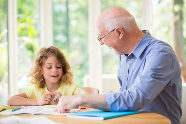 Muž a jeho vnouče dělají po škole domácí úkoly — Stock fotografie